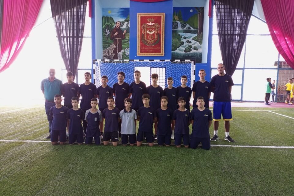 De La Salle youth football squad and coaches on the indoor pitch.