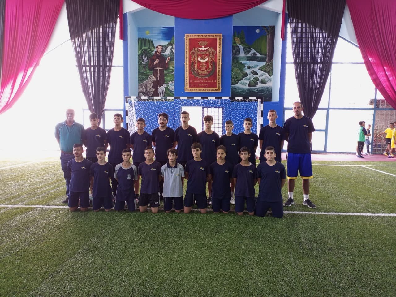 De La Salle youth football squad and coaches on the indoor pitch.