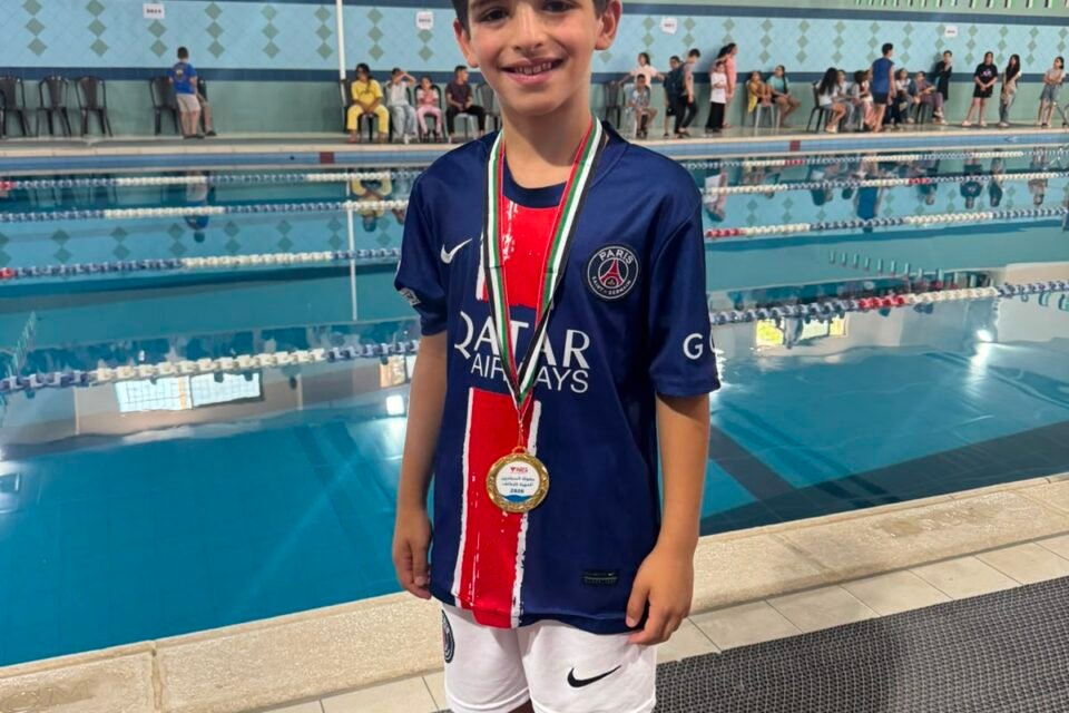 Young De La Salle swimmer wearing a gold medal beside the swimming pool.
